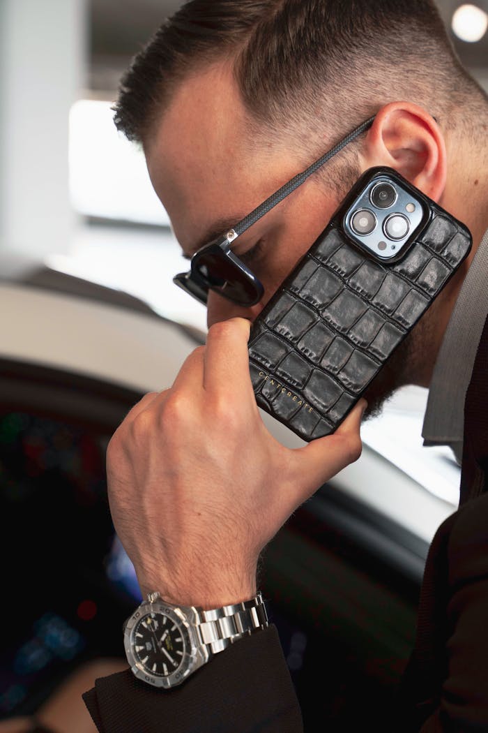 Crafting Captivating Headlines: Your awesome post title goes here Close-up of a stylish man using a luxury iPhone with a leather case, indoors.